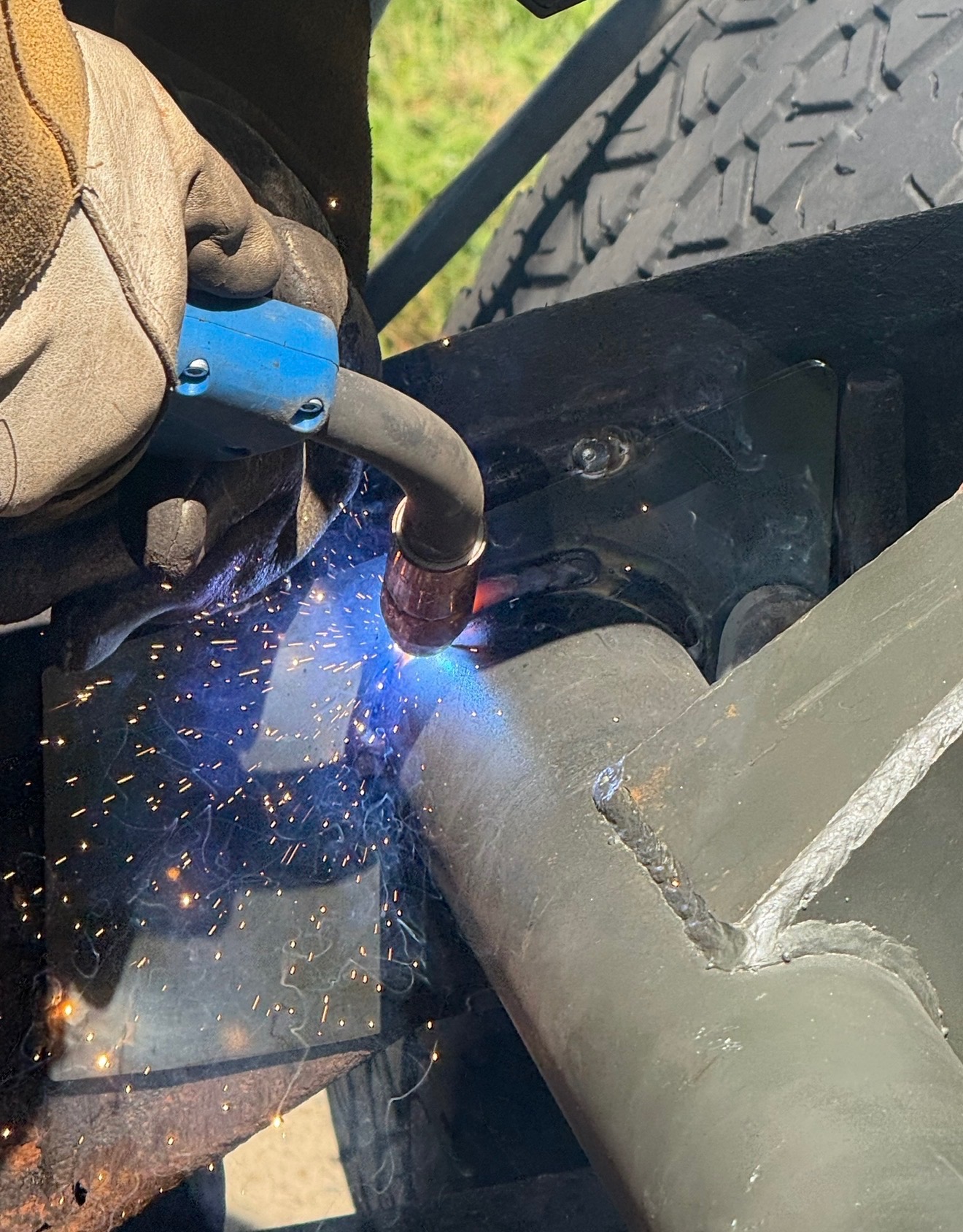 Blue arc weld with sparks flying on auto chassis