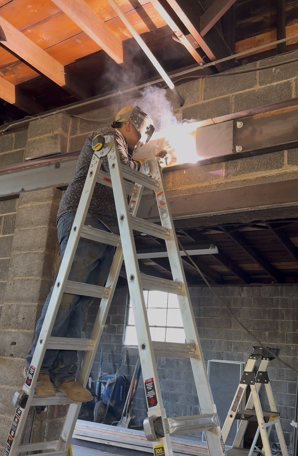 Brian of E&S Welding welding a steel beam into place on a commercial building